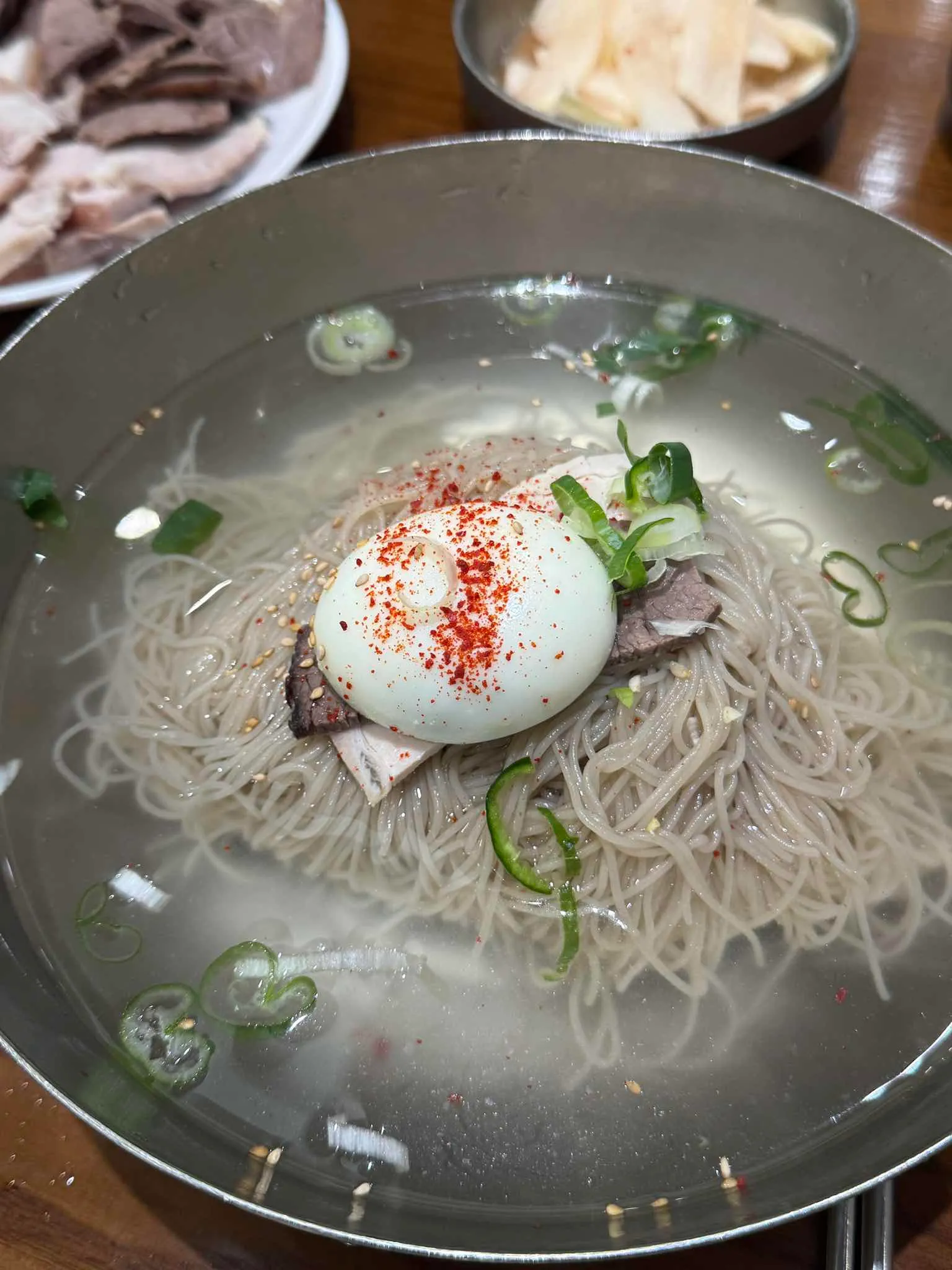 맑은 육수에 가는 메밀 면과 고기, 달걀, 파, 고춧가루를 올린 을지면옥 냉면