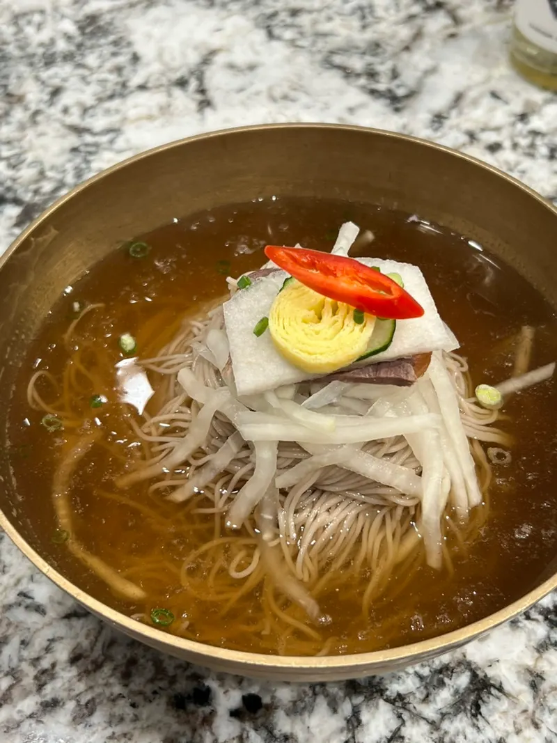 방짜유기 그릇에 순메밀 면과 소고기, 무, 달걀지단, 홍고추를 올린 모연 평양냉면