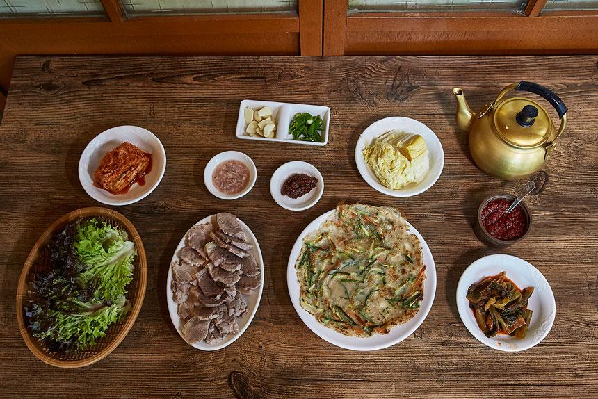남북면옥 돼지수육과 감자전, 채소와 반찬이 놓인 한 상