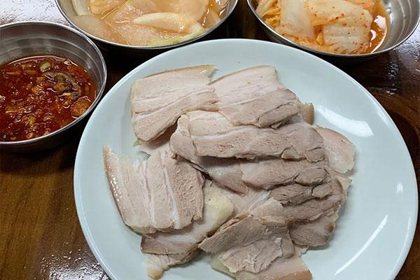 두툼하게 썬 돼지고기 제육과 양념장, 김치가 놓인 필동면옥 한 상